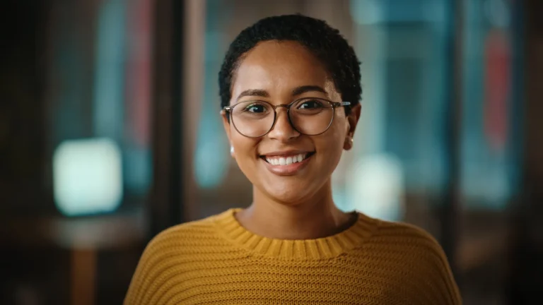 A smiling professional wearing glasses, symbolising confidence and success.
