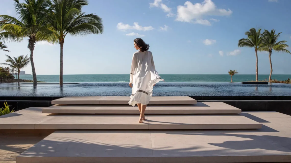A serene image of a guest at Jumeirah Hotel walking towards a stunning sea view with palm trees and a tranquil infinity pool.