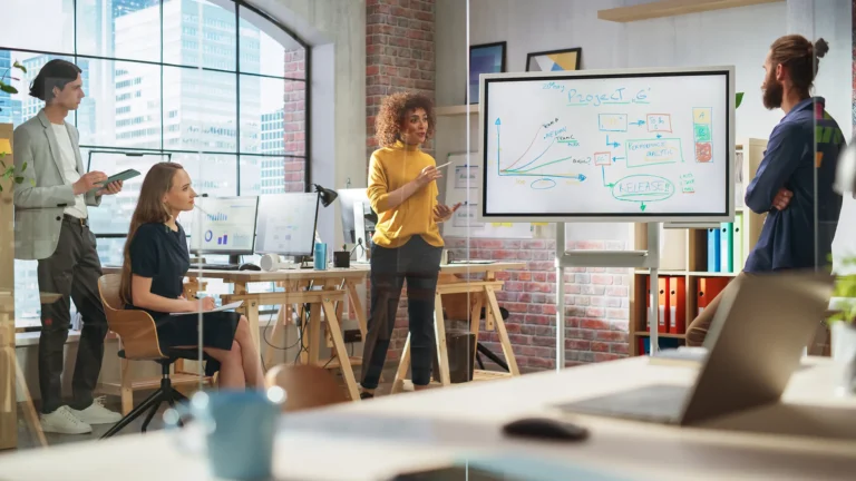 Professional team in a modern office discussing strategies and project metrics on a whiteboard.